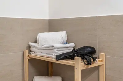 a bathroom shelf with towels and a hair dryer at I Mori-holiday apartment in Palermo