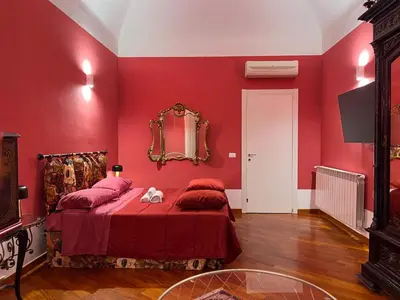 a red bedroom with a bed and a mirror at Le Radici casa vacanze in Palermo