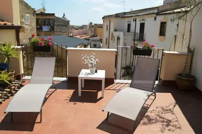two white chairs and a table on a patio at Vecchio Cortile Home Holidays in Palermo
