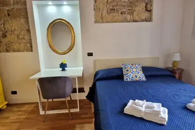 a bedroom with a bed and a table and a mirror at 2 Sicilie Rooms and Suite in Centro in Palermo