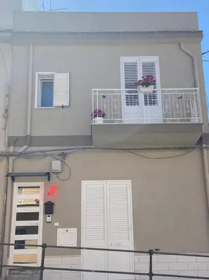 a building with two windows and a balcony with flowers on it at Casa vacanza solemare in Balestrate
