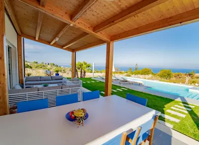 a patio with a table and chairs and a pool at Villa Majestatis in Scopello
