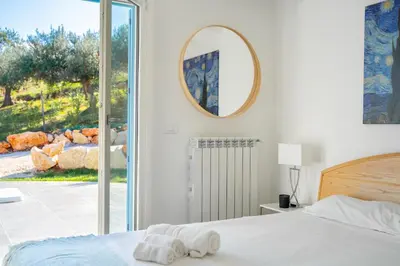 a bedroom with a bed and a mirror on the wall at Villa Majestatis in Scopello