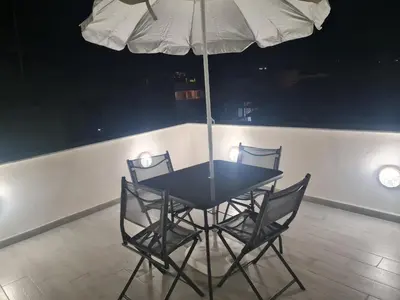 a black table with four chairs and an umbrella at Casetta Bella Nonna Rosetta in Mondello