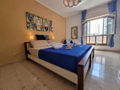 a bedroom with a bed with blue sheets and a window at Lo Scorcio sul Mare by Holiday World in Isola delle Femmine