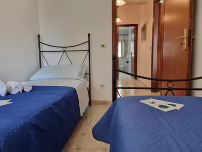 a bedroom with two beds with blue sheets and a doorway at Lo Scorcio sul Mare by Holiday World in Isola delle Femmine