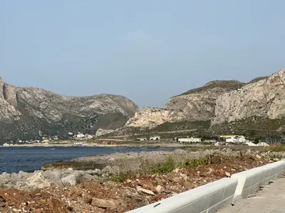 a road next to a body of water with mountains at Lo Scorcio sul Mare by Holiday World in Isola delle Femmine