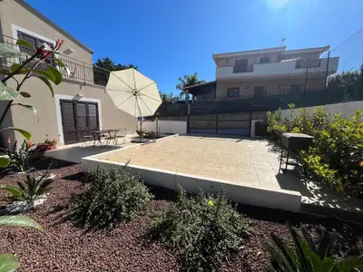 a patio with a table and an umbrella in front of a building at Villa Simo in Altavilla Milicia