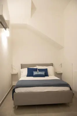 a bedroom with a bed with blue and white pillows at Casa vacanze Marinaro in Castellammare del Golfo