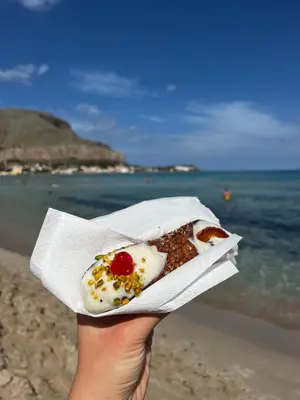 a person holding up a piece of food on the beach at MONDELLO COTTAGE in Mondello