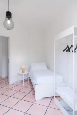 a white bedroom with a bed and a table at MONDELLO COTTAGE in Mondello