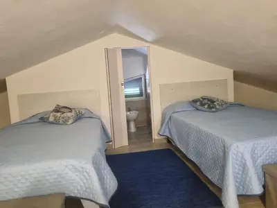 a bedroom with two beds and a bathroom with a mirror at Magnolia in Campofelice di Roccella