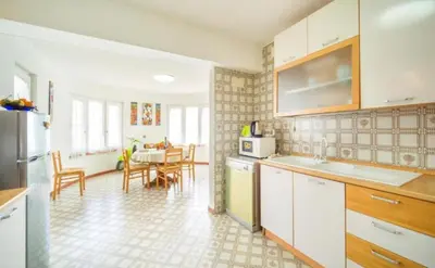 a kitchen with white cabinets and a dining room with a table at La Conca D'Oro in Palermo