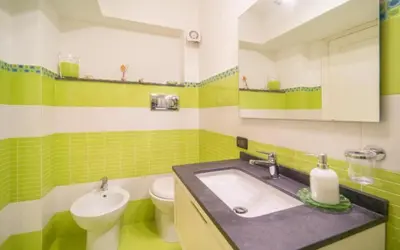 a green and white bathroom with a sink and a toilet at La Conca D'Oro in Palermo