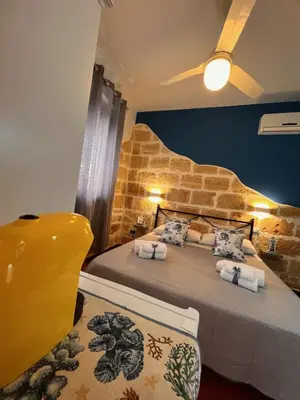a bedroom with two beds and a ceiling fan at Celeste Rooms in San Vito lo Capo