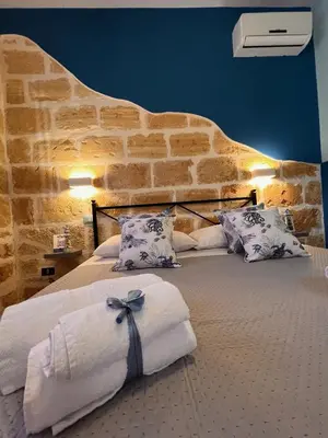 a bedroom with a large bed with a stone wall at Celeste Rooms in San Vito lo Capo