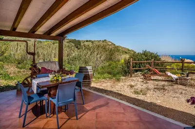a patio with a table and chairs and a view of the ocean at Villa Elena 2 Km from the Natural Reserve of Zingaro in Scopello