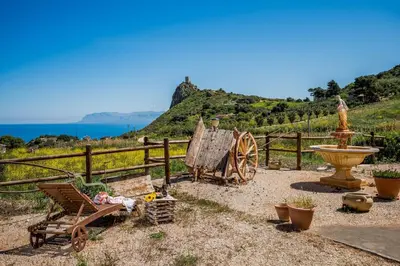 a garden with a wooden fence and a bench and a water fountain at Villa Elena 2 Km from the Natural Reserve of Zingaro in Scopello