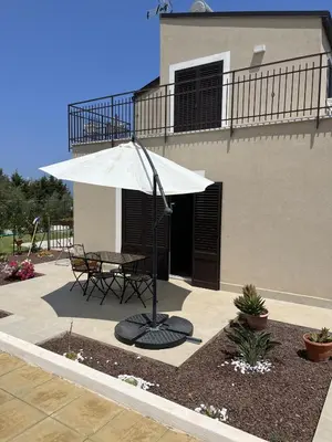 a patio with a table and an umbrella in front of a building at Casa Vacanze Villa Ale in Altavilla Milicia