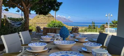 a wooden table with blue and white dishes on it at Villa Ballerina Bianca in Scopello