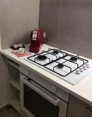 a kitchen counter with a stove top with a red appliance at Casa Marele in Palermo