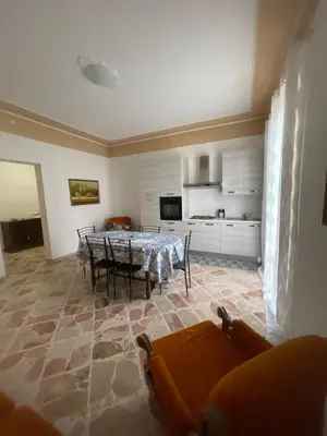 a living room with a table and a kitchen at APPARTAMENTO MAESTRALE in Balestrate