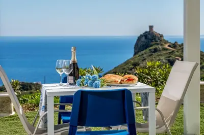 a table with two chairs and a bottle of wine at Villa Holidays Vista Torre Bennistra in Scopello in Scopello
