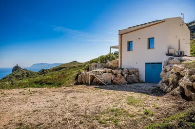 a house on a hill with the ocean in the background at Villa Holidays Vista Torre Bennistra in Scopello in Scopello