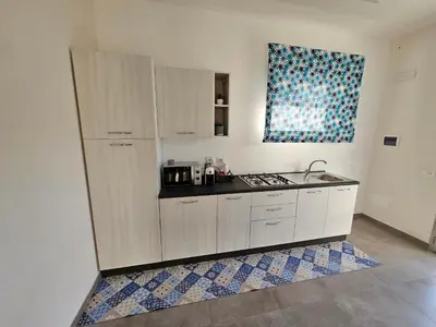a kitchen with white cabinets and a sink and a window at Casa vacanze I colori del mare in Alcamo Marina