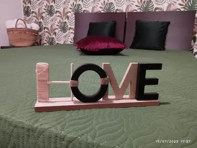 a wooden sign that says love on a bed at La casa di Nanà in centro in Palermo