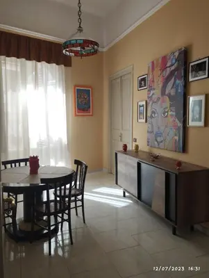 a living room with a dining room table and a painting at La casa di Nanà in centro in Palermo