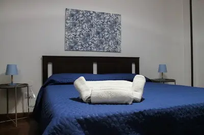 a blue bed with a white pillow on it at Alexander House in Palermo