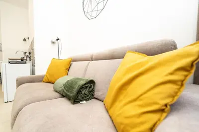 a gray couch with yellow pillows in a living room at Valguarnera Studio Apartments in Palermo