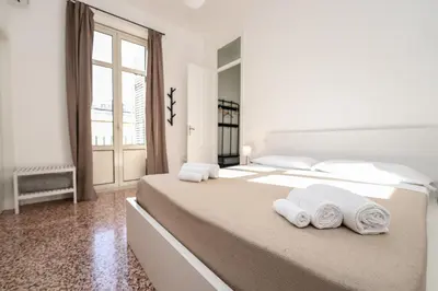 a white bedroom with a large bed with towels on it at Valguarnera Studio Apartments in Palermo