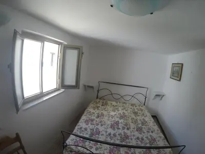 a small bedroom with a bed with a floral blanket at Casa Vacanza Terrazza sul Mare in Castellammare del Golfo