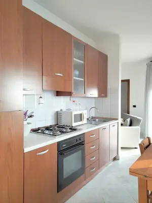 a kitchen with wooden cabinets and a microwave at Finestra sul Mare di Alessandro in Balestrate