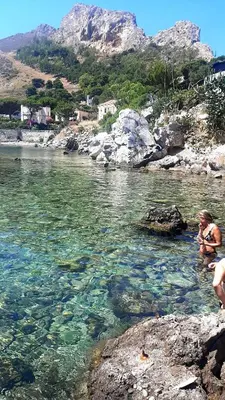 a woman sitting on rocks in a body of water at La casetta degli ulivi in Palermo