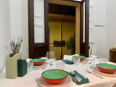 a white table with green plates and wine glasses at Casa 900 in Castellammare del Golfo