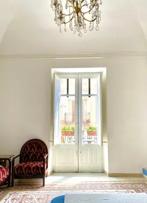 a room with a chandelier and a chair and a window at Casa 900 in Castellammare del Golfo