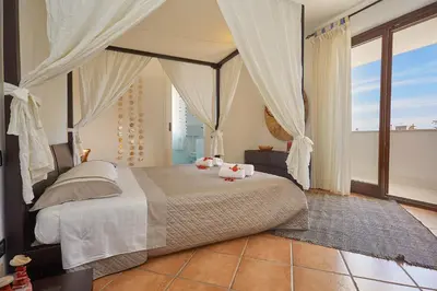 a bedroom with a bed with white sheets and curtains at Villa Costantino in Trappeto