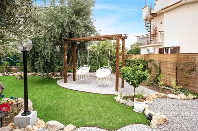 a garden with two white chairs and a swing at Anastasia's House in Trabia
