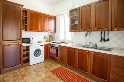 a kitchen with wooden cabinets and a washing machine at Anastasia's House in Trabia