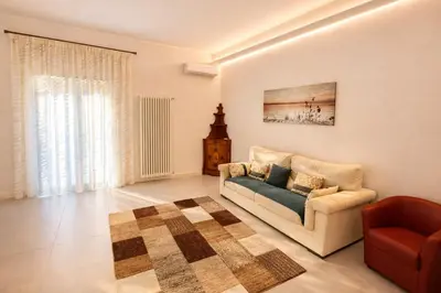 a living room with a couch and a chair at Giardino Lussemburgo, Elegante e confortevole appartamento tra Mondello e il centro storico di Palermo in Palermo