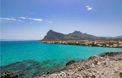 a beach with blue water and mountains in the background at Amazing Home In Trappeto With Wifi in Trappeto