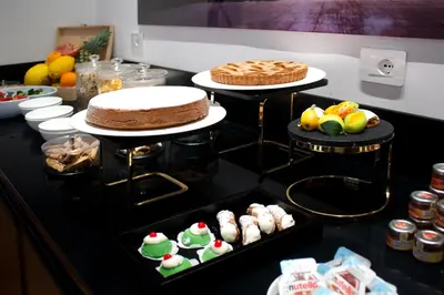 a table with three tiers of cakes and other desserts at Palazzo Cartari in Palermo