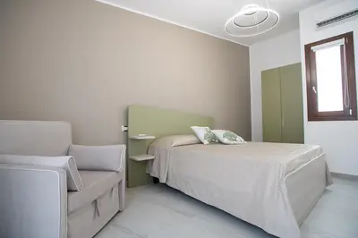 a bedroom with a bed and a chair at La Chiostrina 2 in Castellammare del Golfo