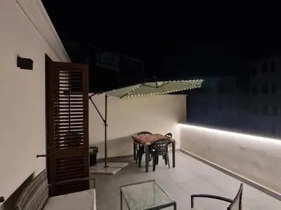 a table and chairs on a balcony with an umbrella at La Chiostrina 2 in Castellammare del Golfo
