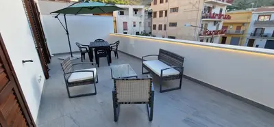 a balcony with chairs and tables and an umbrella at La Chiostrina 2 in Castellammare del Golfo