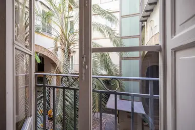 a window view of a building with a palm tree outside at Aurora Apartment by Domus Sicily in Palermo