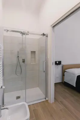 a bathroom with a shower and a sink and a bed at Ballaro' House in Palermo